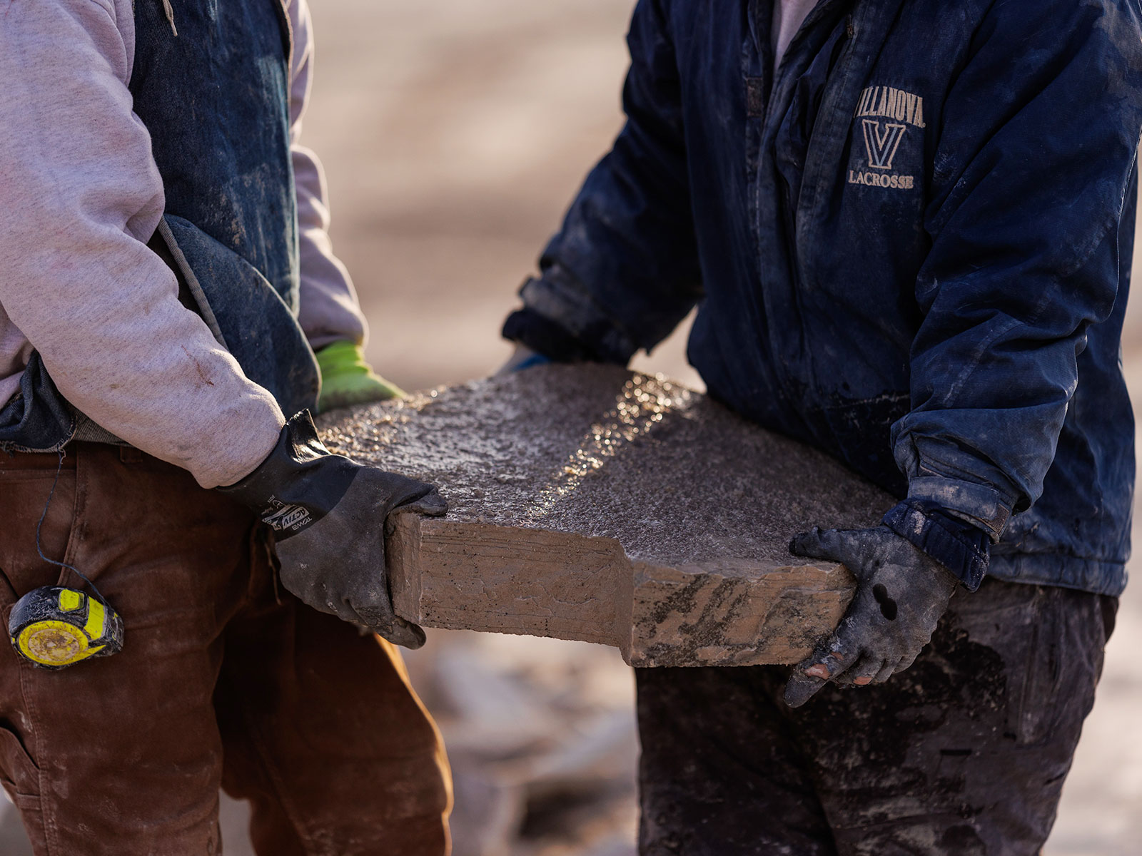 Close up of two men carrying a stone slab